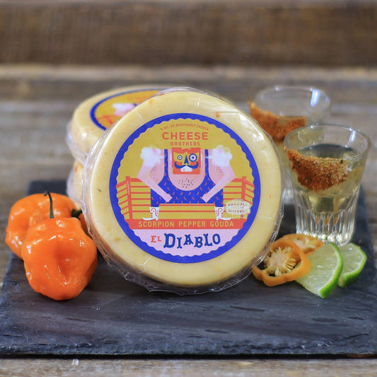 Cheese wheel with 'El Diablo' label on a wooden board with peppers and lime