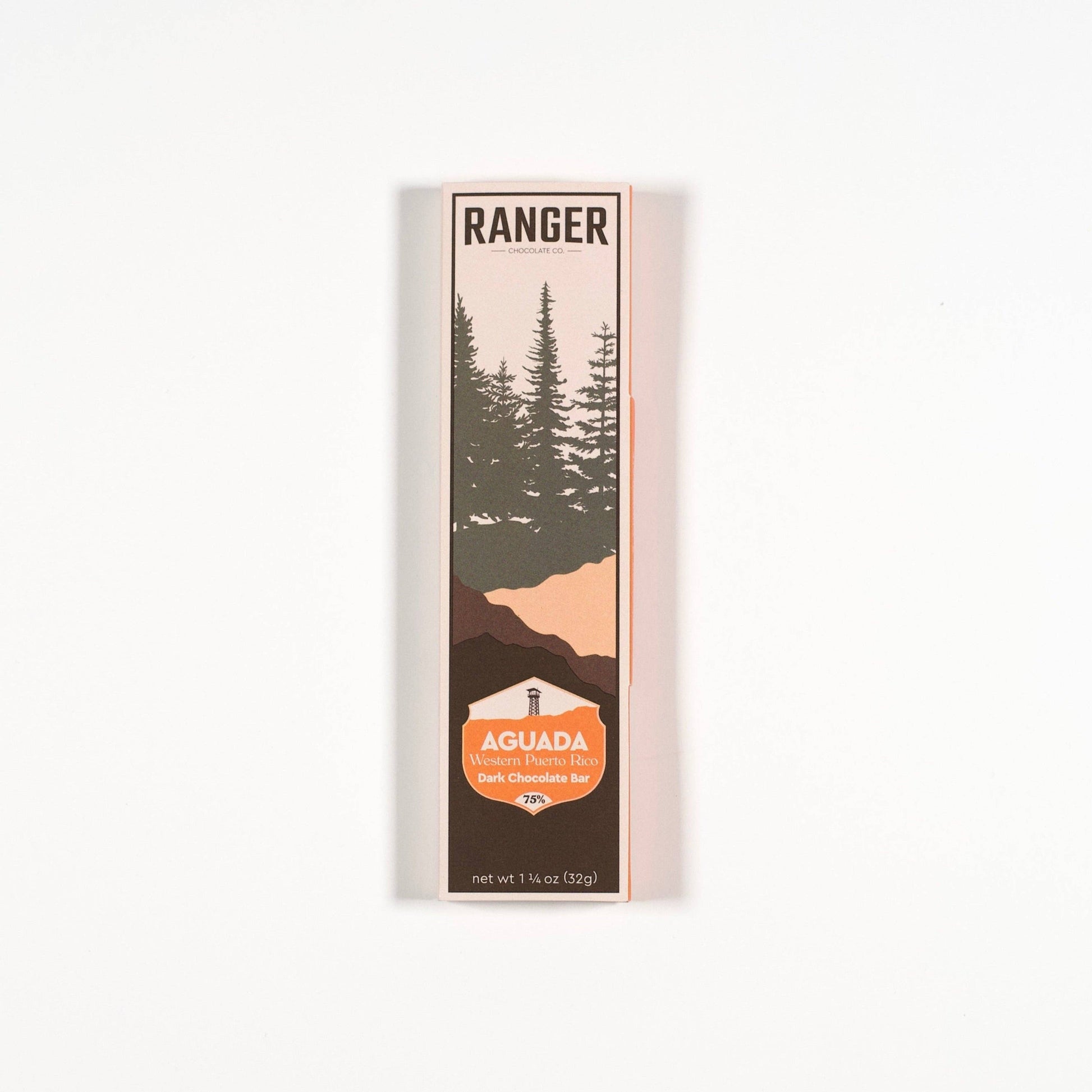 A tall, narrow package of Ranger Aguada dark chocolate bar with a minimalist landscape illustration of pine trees and mountains, set against a plain white background.